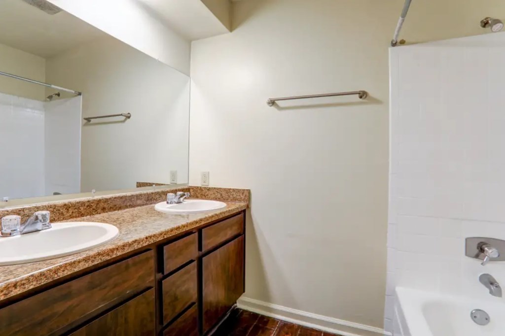 A bathroom with a white tub and a brown vanity.